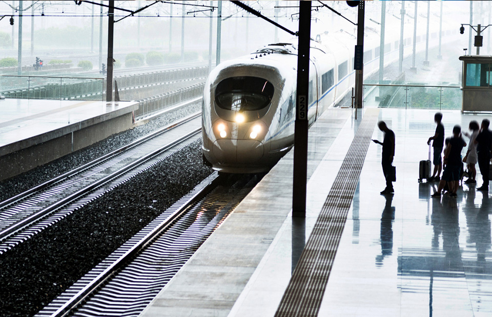 Im Abendlicht in einen Bahnhof einfahrender Zug