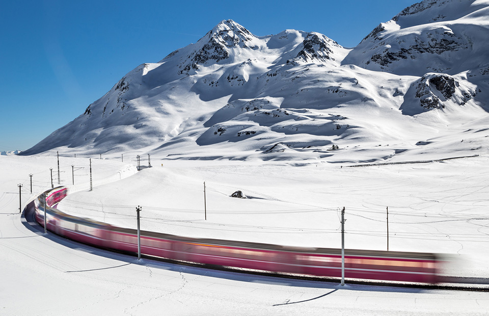 Swiss train travels through a snow-covered alpine landscape