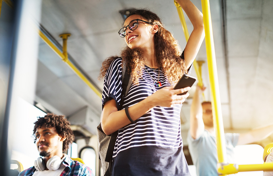 Young woman using cell phone in the bus