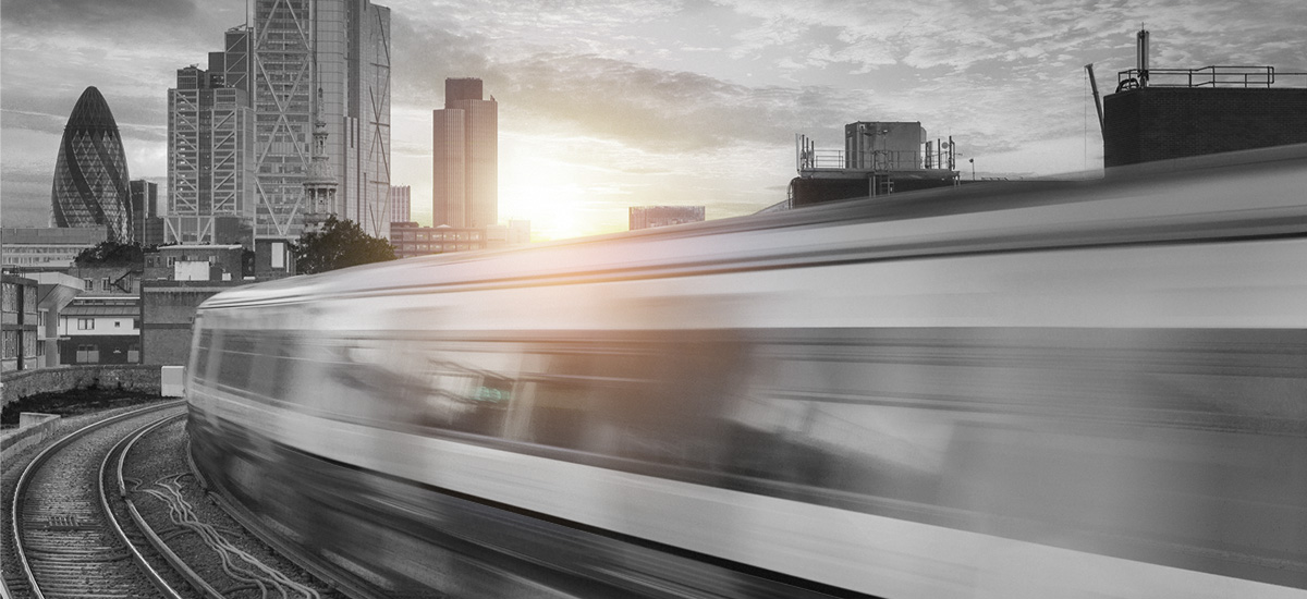 Blurred commuter train driving into London City at sunset