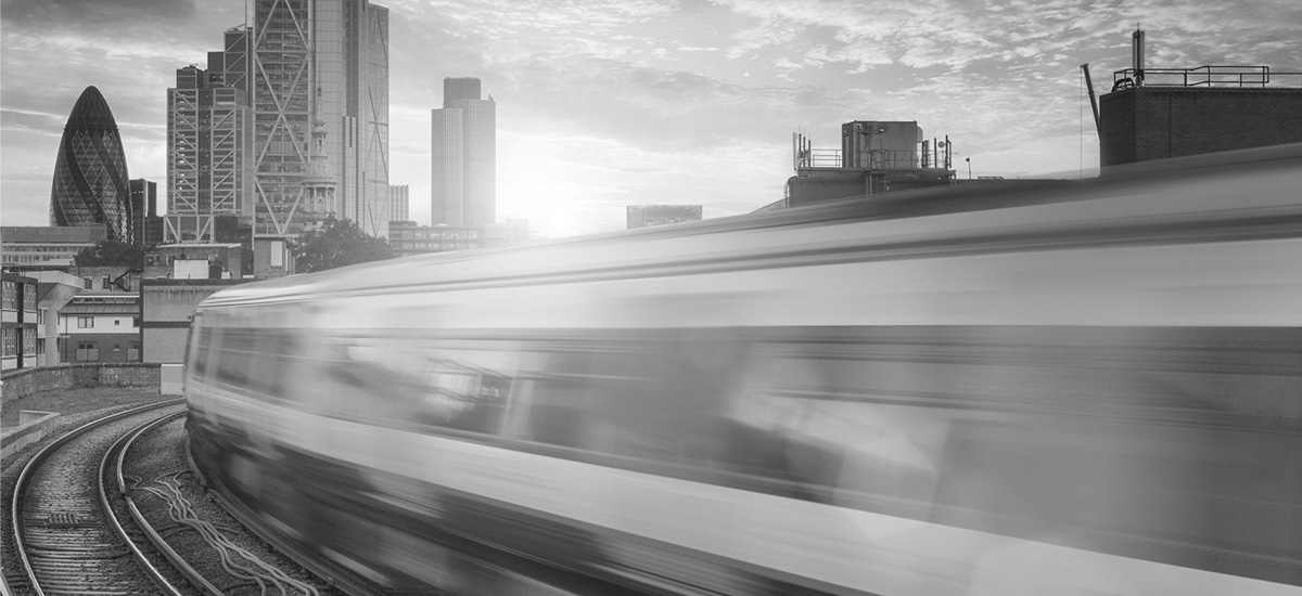 Verschwommener Pendler-Zug fährt im Sonnenuntergang in die London City.
